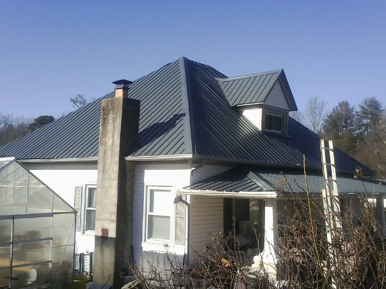 Dark blue standing seam metal roof on a white farmhouse with dormer — Slate & Tile Roof Repair by Roofing Brothers in Parachute