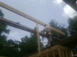 Carpenter setting a ridge beam over a new addition frame — Ice Dam Removal by Roofing Brothers in Parachute