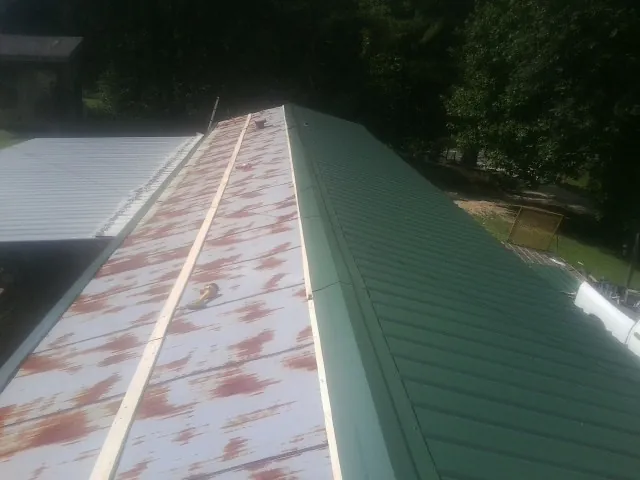 Old rusted panels beside newly installed green metal roofing — Wind Damage Roof Repair by Roofing Brothers in Parachute