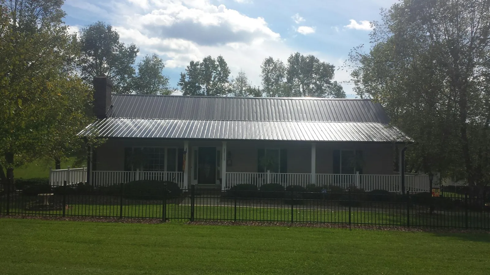 Gray metal roof on a brick ranch with a full width front porch — Gutter Guard Installation work by our crew in Parachute
