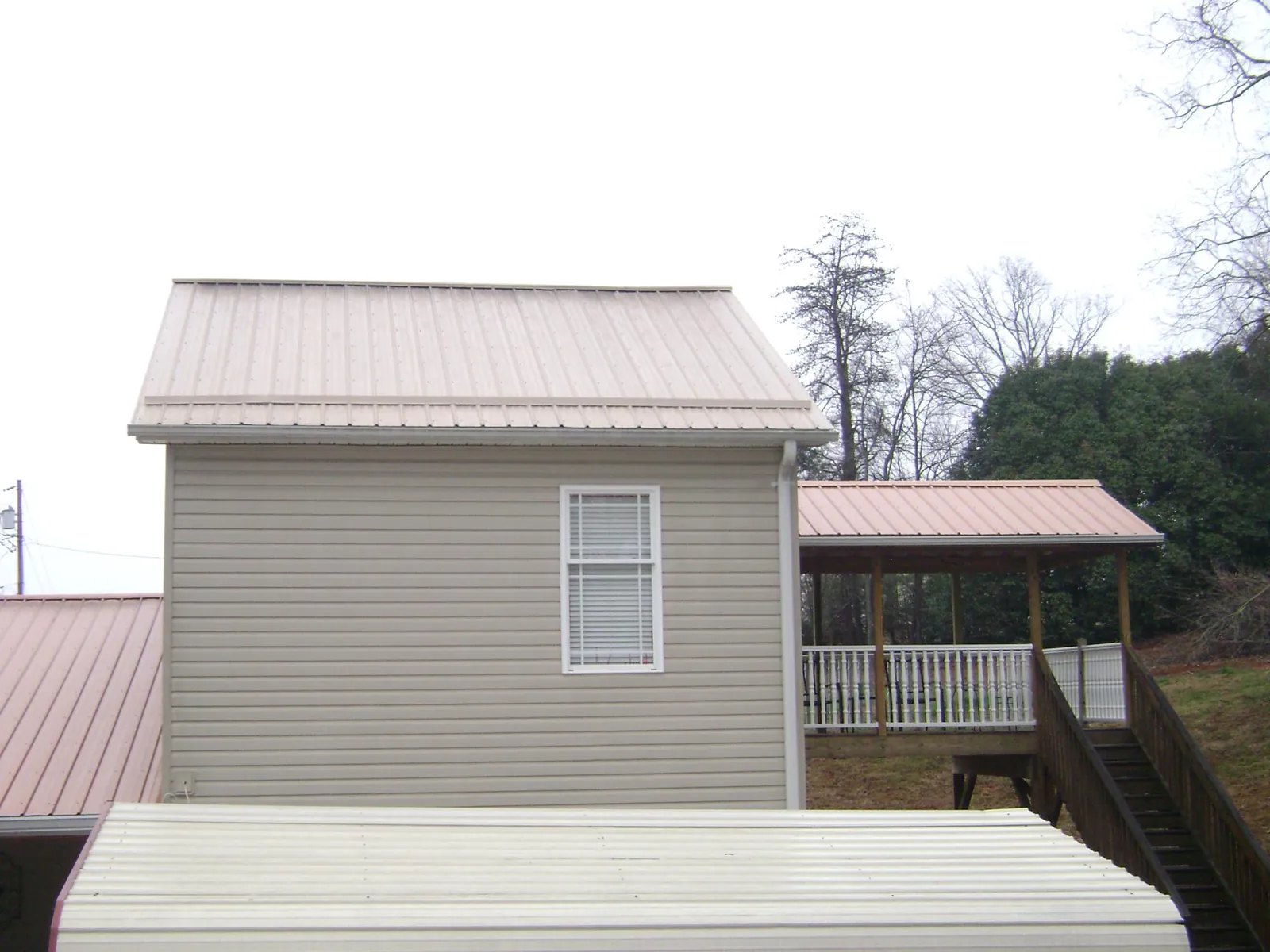 Tan metal roofs on a two story addition and attached porch, from a Roof Replacement job in Parachute