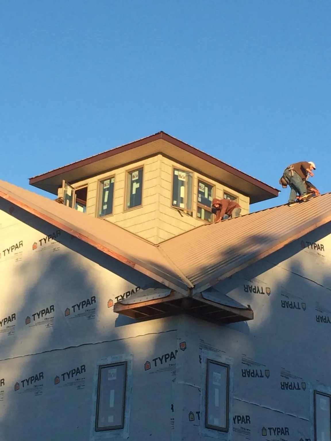 Roofers working around a rooftop cupola on a new metal roof at sunset — Roof Waterproofing in Parachute by Roofing Brothers